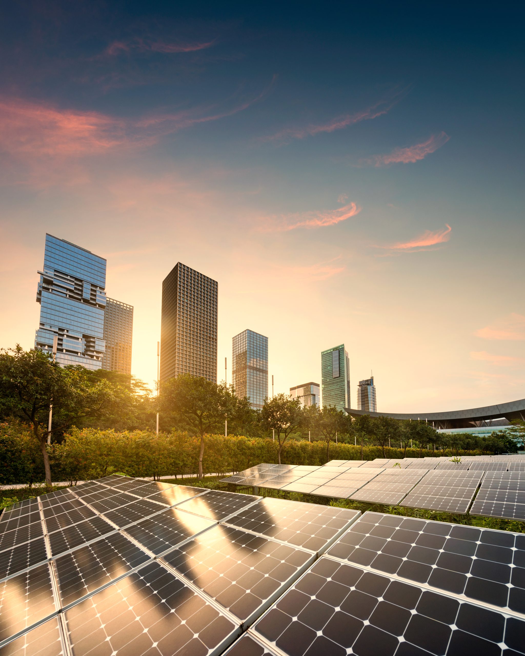 Sun shining in background of city with solar panels in the foreground