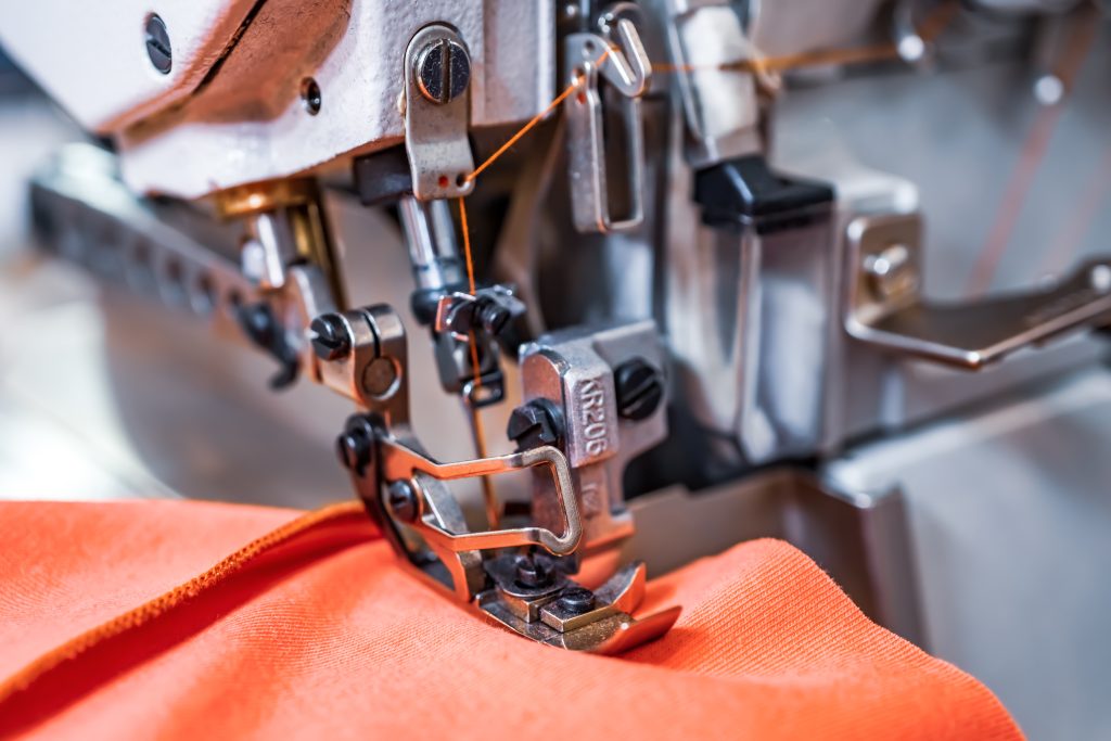 Close up of professional sewing machine with orange fabric